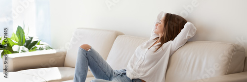 Beautiful woman in casual clothes resting leaned on leather sofa breath fresh air looks in distance enjoy weekend, modern apartment, vacation concept. Horizontal photo banner for website header design
