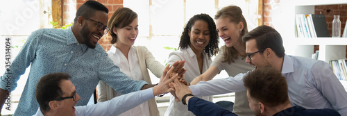 Happy multi ethnic colleagues celebrating business success giving high five show support share common victory. Teambuilding, teamwork, unity concept. Horizontal photo banner for website header design photo