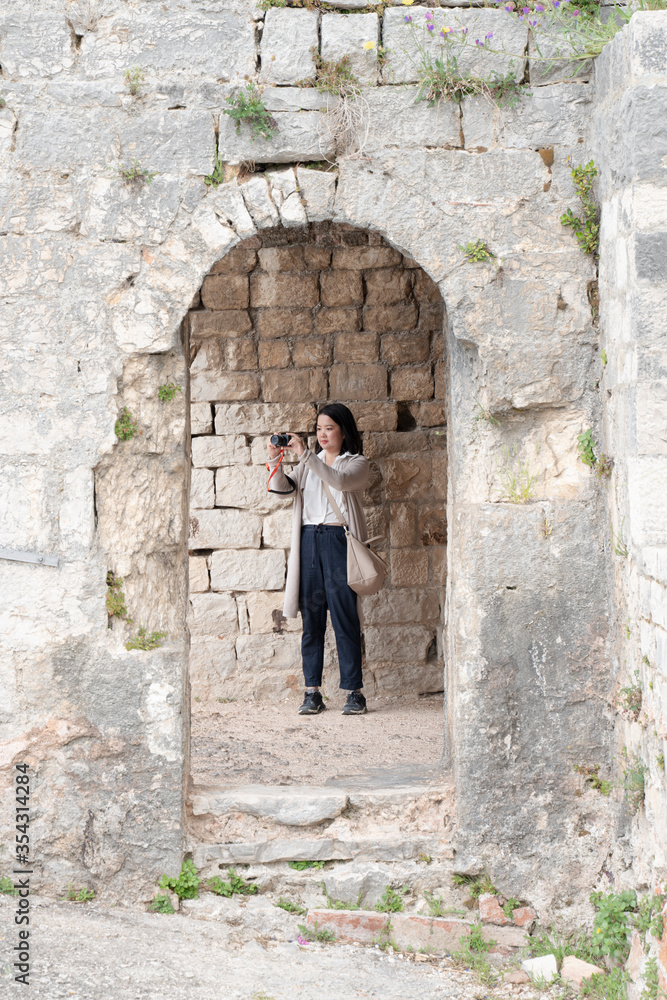 Young female Asian tourist traveling in the stone chateau, taking photograph of her surrounding