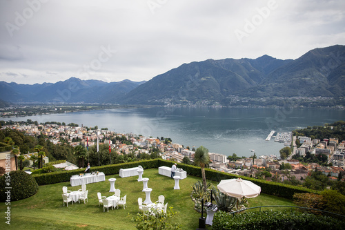 in backyard of villa in Tuscany there is banquet table decorated with cotton and eucalyptus compositions, glasses, candles and plates are placed on table,