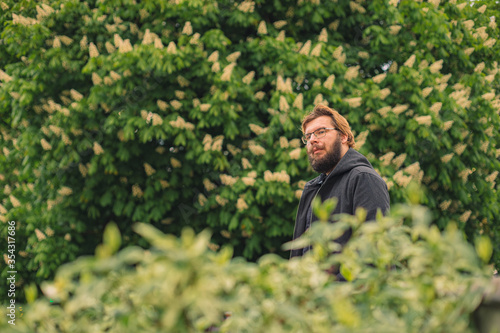 tender man portrait in garden foliage green nature environment middle adult bearded person posing photography walking alone outside © Артём Князь