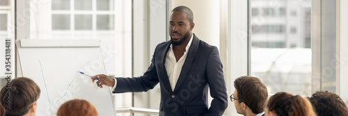 Εκτύπωση καμβά Confident African business coach gives presentation on flip chart, consults clients, teach employees, explain corporate strategy at seminar concept
