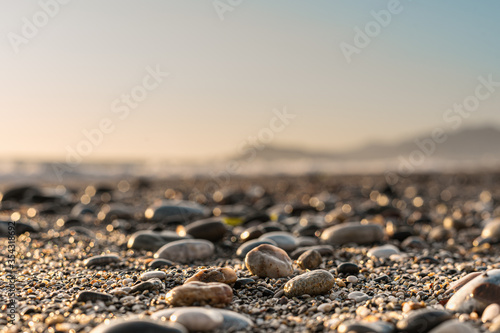Close-up of pebble beach with light reflecting on stones against the blurred sky