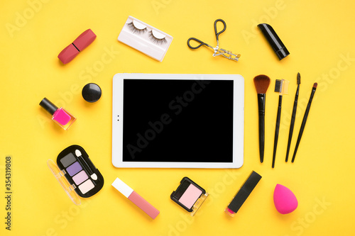 Tablet, set of professional decorative cosmetics, makeup tools and accessory of trendy pink color isolated on yellow background Beauty, fashion, party, shopping concept Flat lay composition Mock up