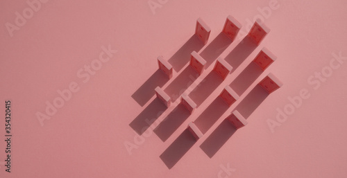 Fotografie The domino chips pink on a pink background view from above make shadows on the background