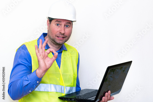 Attractive caucasian Technician Holding Laptop Over White Background.Makes all kinds of grimaces-eyes closed, upset, thinking, shows thumb up, and ok gesture... © ARVD73
