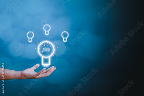 Inspiration, idea, and creative concept. Businessman holding light bulb sign on hand on blue bokeh background with copy space for text.