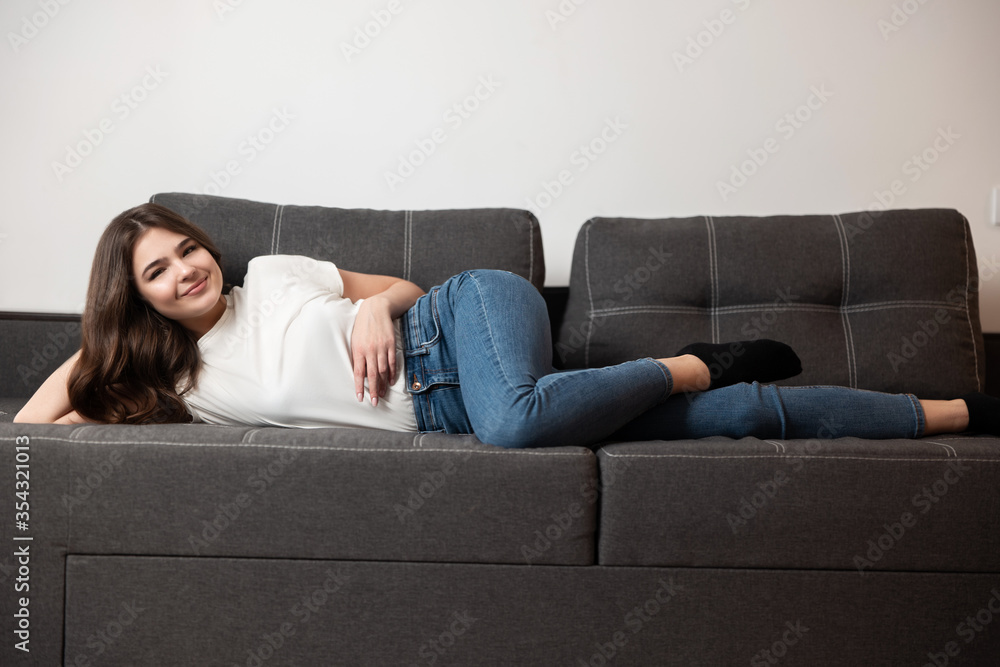 young beautiful brunette sexy tired woman lying on the sofa in her appartment after hard work day ,feeling cozy at home young beautiful brunette sexy tired woman lying on the sofa in her appartment after hard work day ,feeling cozy at home