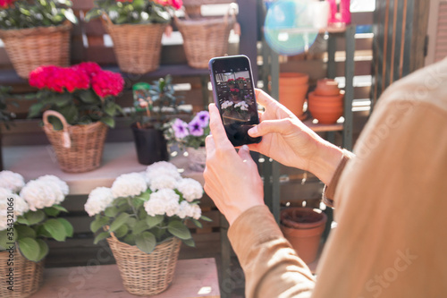 A woman takes photos of flowers on her phone. Buying a home plant. Flower sales. Flower market. Retail sale of flowers