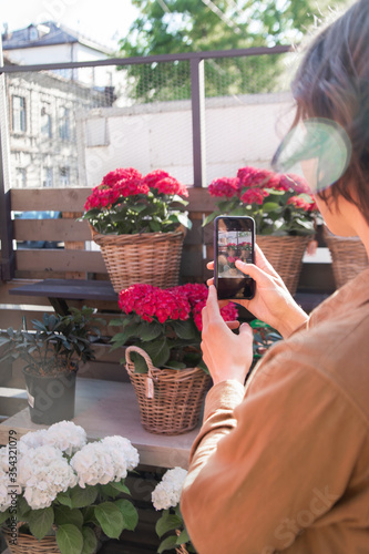 A woman takes photos of flowers on her phone. Buying a home plant. Flower sales. Flower market. Retail sale of flowers