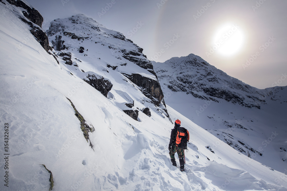 Climber hiking on the mountain in winter. Tatra Mountains with Kościelec peak. Snowy scenery.