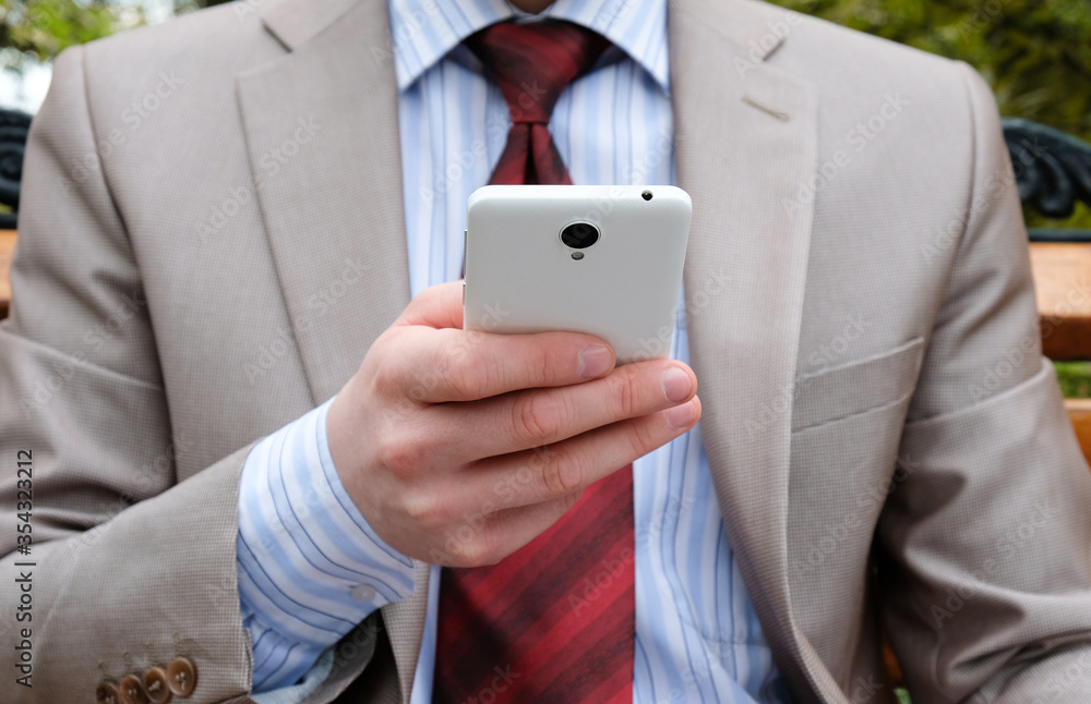 Φωτογραφία Young male businessman holds a phone in his hands on the street
