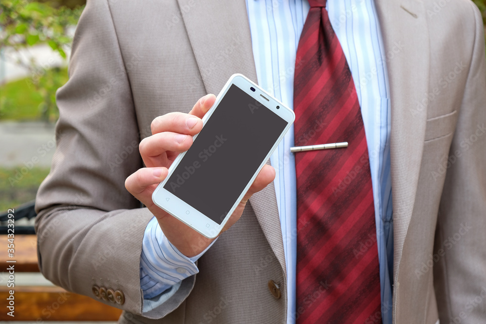 Φωτογραφία Young male businessman holds a phone in his hands on the street
