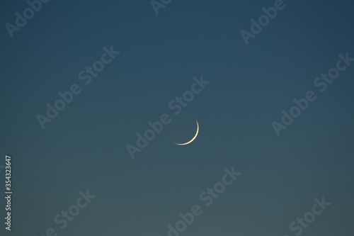 Fotografie Photo of a new moon with the ashen light of the moon in the blue evening sky