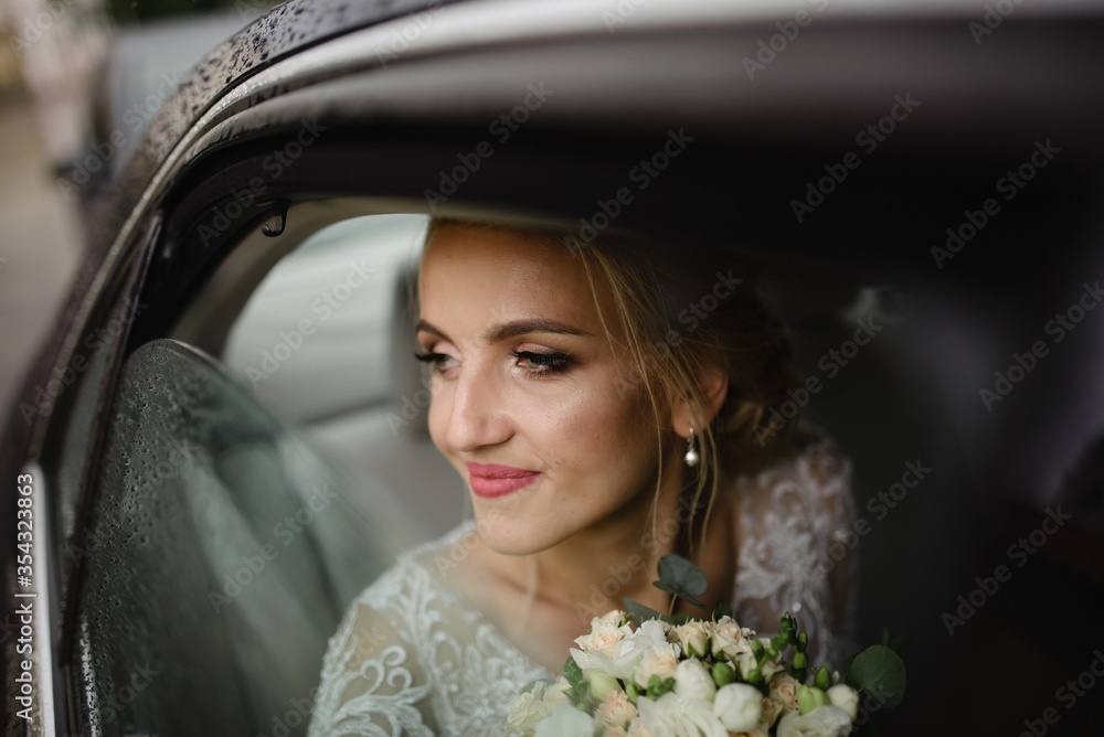 Beautiful blonde bride looks out the car window. Rainy weather.