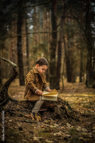 Little cute child is reading in the Forrest