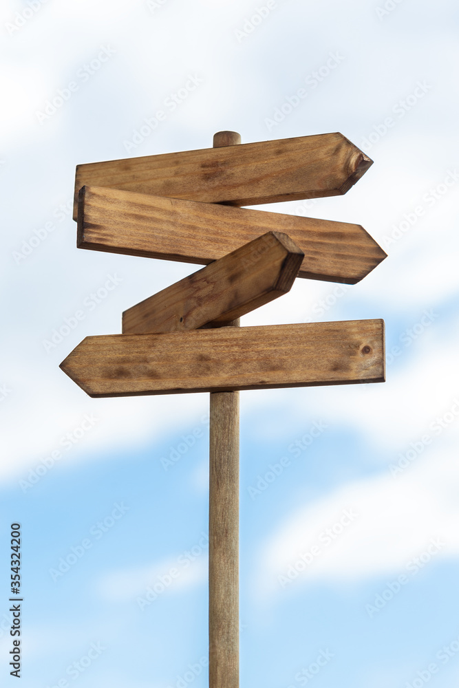 Wooden sign post isolated on blue sky with white clouds. Direction concept. Mock up, template Wooden sign post isolated on blue sky with white clouds. Direction concept. Mock up, template