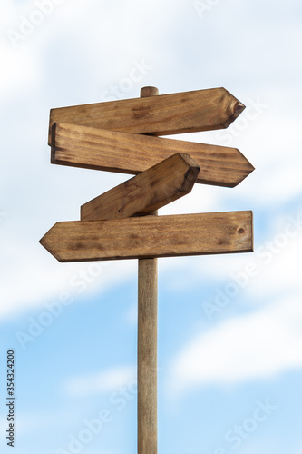 фотографія Wooden sign post isolated on blue sky with white clouds