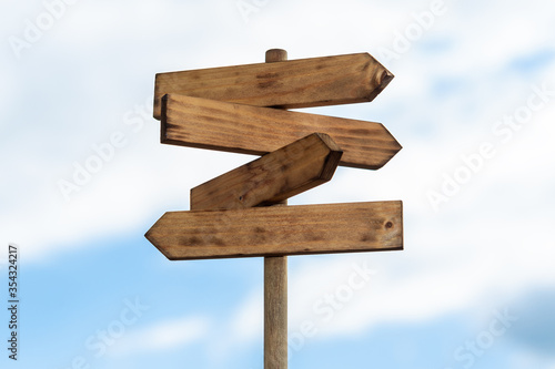 Wooden sign post isolated on blue sky with white clouds. Direction concept. Mock up, template