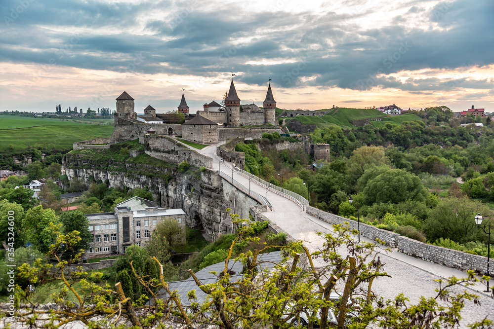 Kamianets-Podilskyi Castle, Ukraine and the road leading to it at sunset in summer. Horizontal orientation.