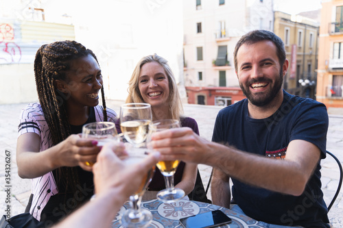 Friends drinking drinks on the terrace of a bar. The camera toasts with his friends happily. New normality concept