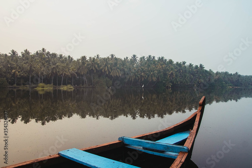 Wooden boat on the backwater canals on a background of tropical forest with palm trees. Copy, empty space for text