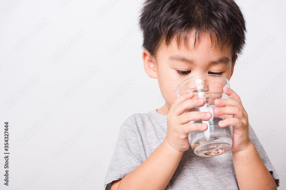 Closeup Asian face, Little children boy drinking water from glass on white background with copy space, health medical care Closeup Asian face, Little children boy drinking water from glass on white background with copy space, health medical care