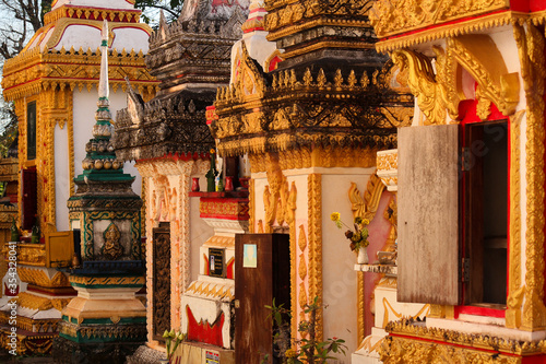Stony and colorful painted stupas and graves of buddhist staff or monks on a sunny afternoon at a temple site in Siamese Lao PDR, Southeast Asia