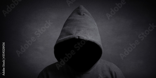 faceless person wearing black hoodie hiding face in shadow - mystery crime conspiracy concept photo