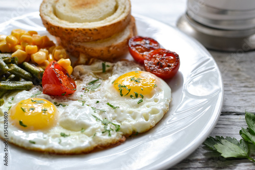 Fried eggs with tomatoes, green beans, corn and toast. English vegetarian breakfast. Coffee and fried eggs close-up.