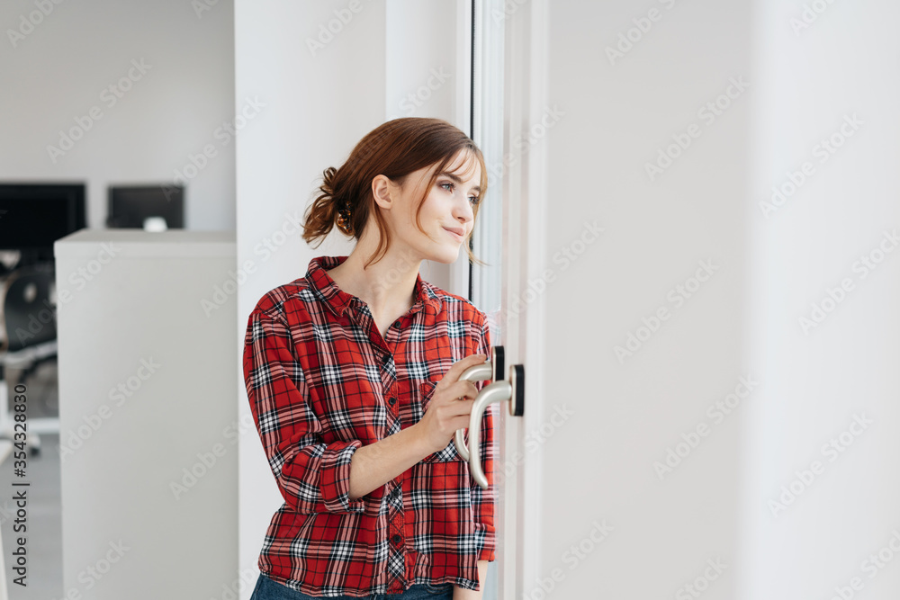 Young woman standing waiting at an office entrance Young woman standing waiting at an office entrance