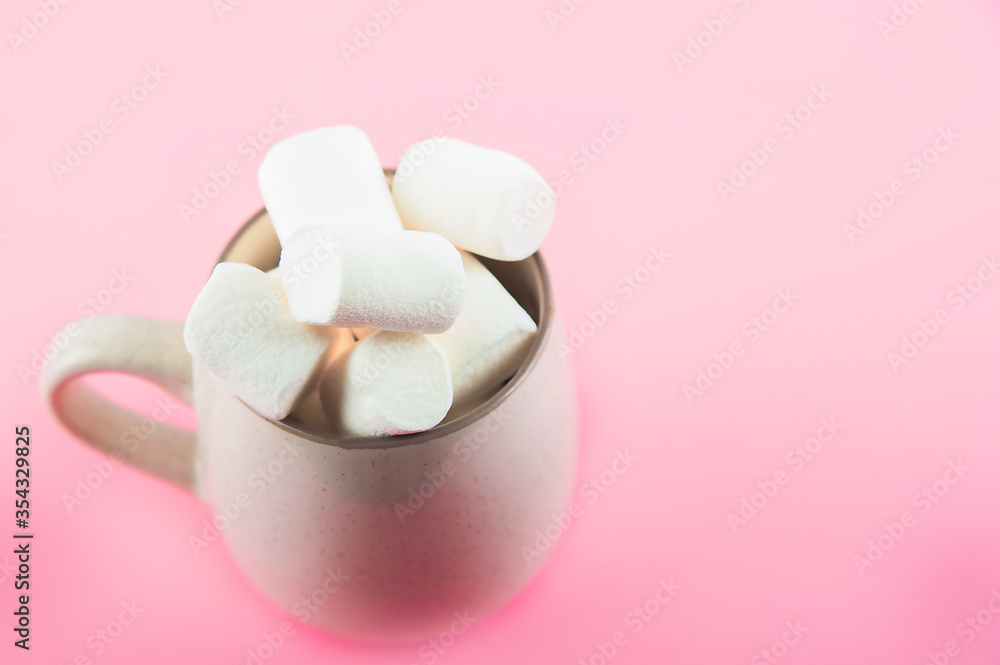 Marshmallows close-up and copy space on a pink background. Marshmallows in an earthenware mug.