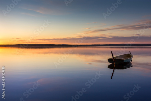 One small fishing boat on a pier by the lake during sunset. Long exposure photo