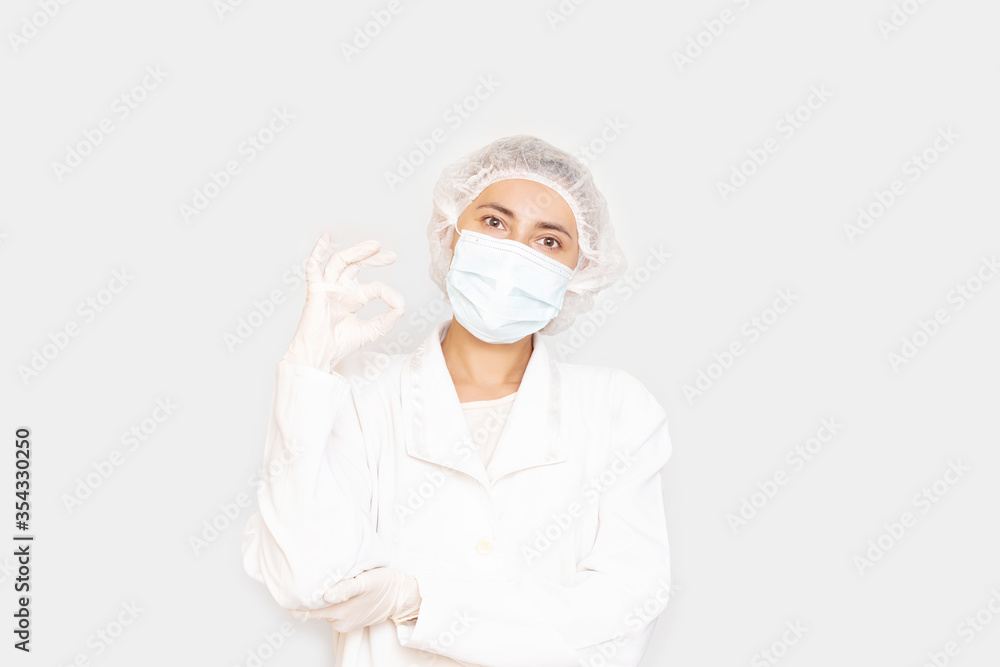 Portrait of a woman adult young in a medical mask, gloves and cap on an isolated background Portrait of a woman adult young in a medical mask, gloves and cap on an isolated background