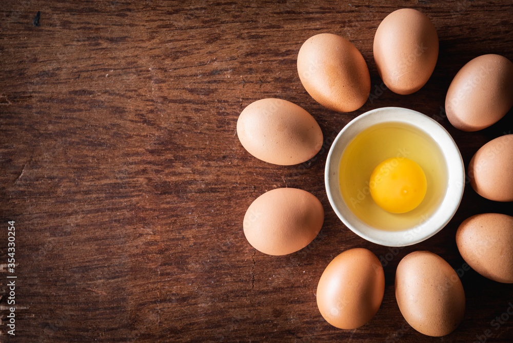 Broken egg shells and raw egg in small bowl line up circle at wooden background for menu and recipe Broken egg shells and raw egg in small bowl line up circle at wooden background for menu and recipe