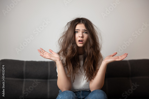 brunette young woman with tangled long hair looks desparate and unhappy with her hairstyle, bad hair day concept photo