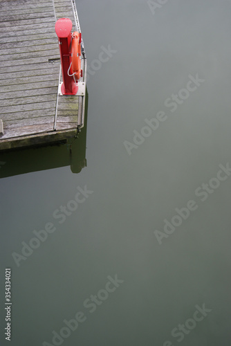 ein Steg mit rotem Rettungsring umgeben von Meerwasser