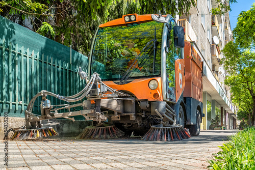 Street cleaner vehicle, road sweeper cleaning on the pavement in city of Slovakia photo