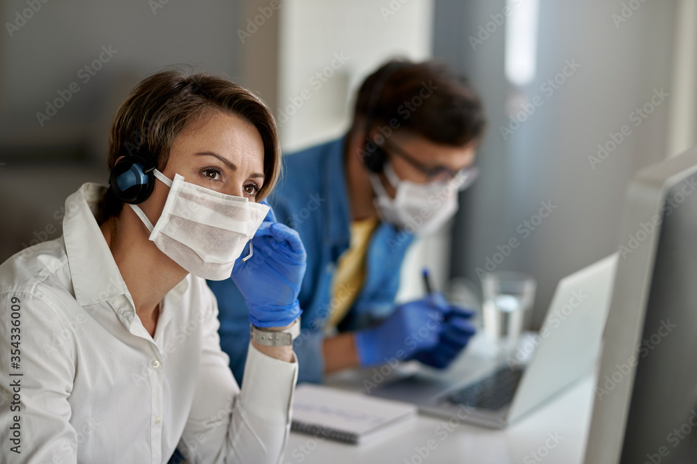 Pensive call center agent communicating with customer while working during coronavirus epidemic. Pensive call center agent communicating with customer while working during coronavirus epidemic.