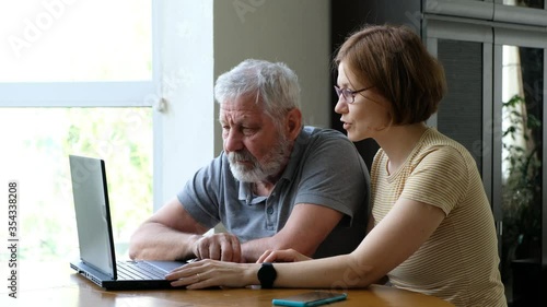 Senior elderly man grandfather and adult daughter, helping him with computer