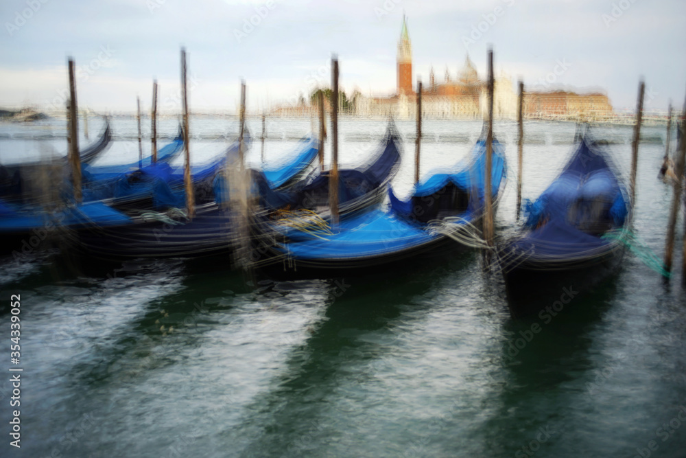 Venice, Italy - August 25, 2018. Gondolas at the pier overlooking the San Giorgio Maggiore. Gondolas at the pier in Venice.