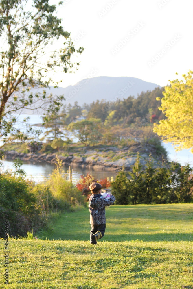 A child playing outside with a soccer ball on a grassy field during a break while home schooling in the Gulf Islands of Canada. A child playing outside with a soccer ball on a grassy field during a break while home schooling in the Gulf Islands of Canada.