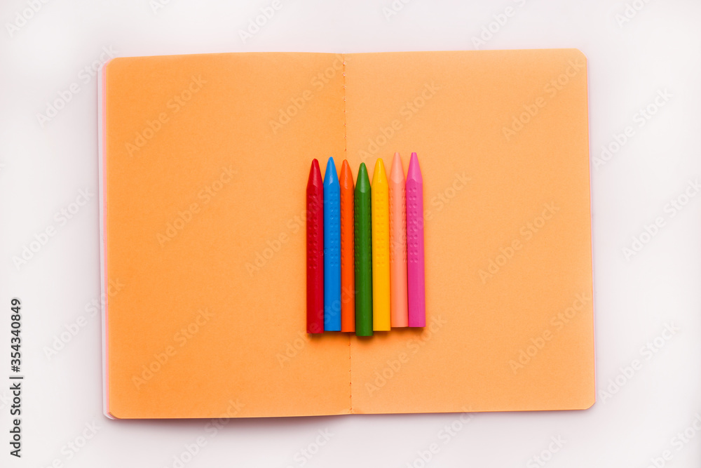 The concept of the school year and drawing. Crayons of different colors on a notebook The concept of the school year and drawing. Crayons of different colors on a notebook