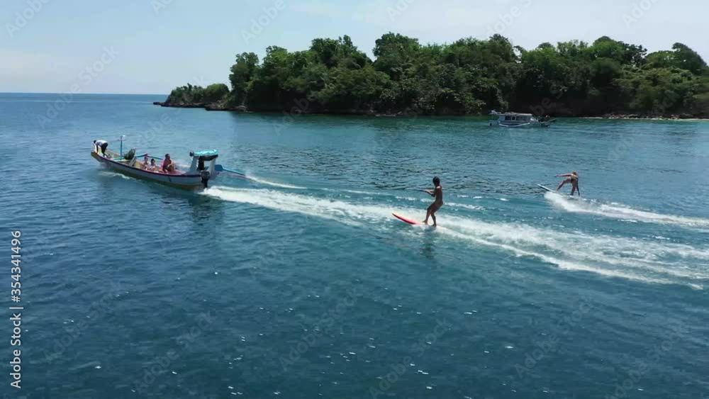 Two young women are being pulled and dragged by a speed boat with a tow ...