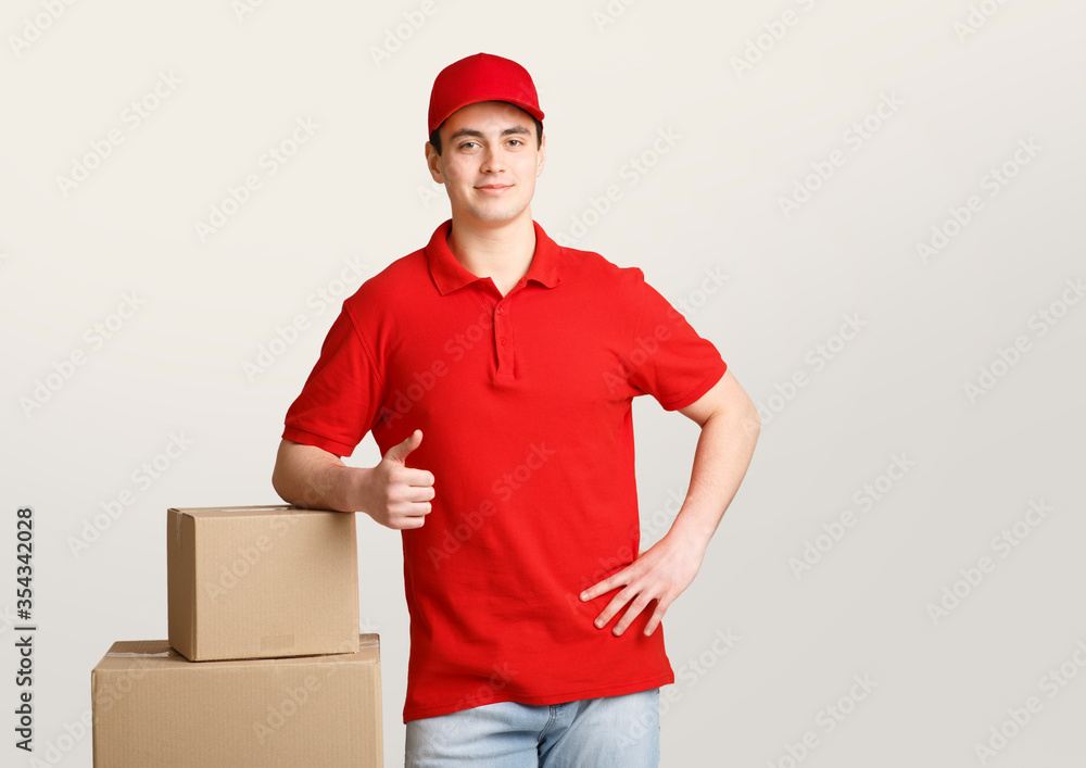 Fast delivery. Courier leans on boxes and shows sign perfectly with his hand Fast delivery. Courier leans on boxes and shows sign perfectly with his hand