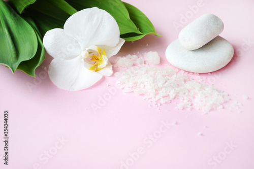 Flat lay composition with white spa sea salt and white orchid with space for text on pink background. Spa cosmetic and Beauty concept  top view. Meditation and minimalism. copyspase flatlay.