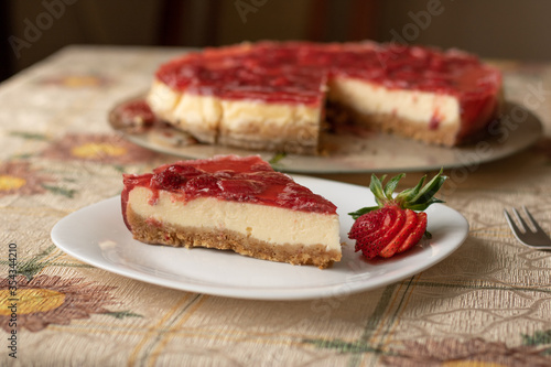 New York Cheesecake with Strawberries in a white plate on a tablecloth, fork and tray, homemade