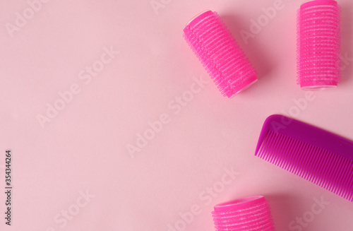 Hairdressing services-banner-comb and curlers on a pink background, place for the inscription, top view.