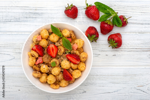 Mueslis with berries in a  white cup on the table, macro photo