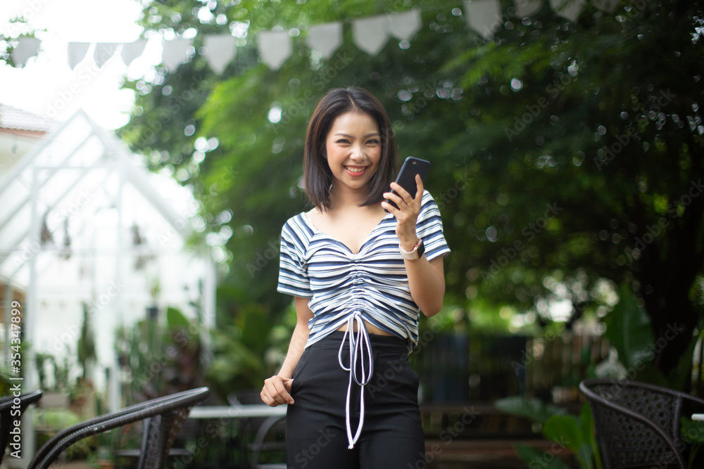 Young woman holding a smart phone on a city street.